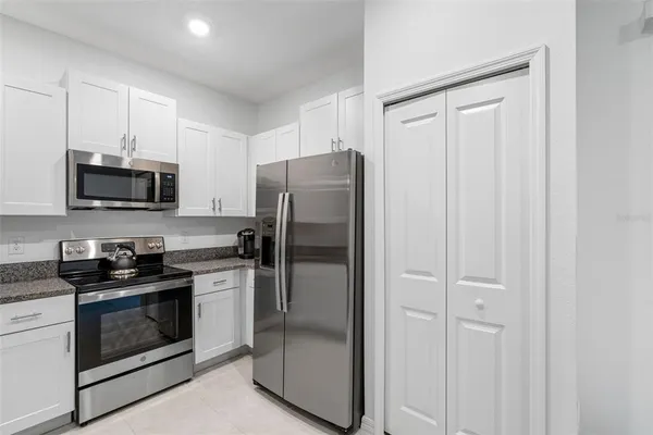 a kitchen with stainless steel appliances granite countertop white cabinets and a refrigerator