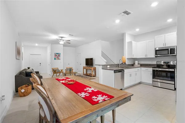 a kitchen with stainless steel appliances kitchen island granite countertop a sink dishwasher and white cabinets with wooden floor