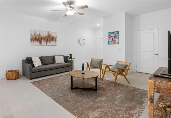 a living room with furniture and a dining table with a potted plant on a dresser
