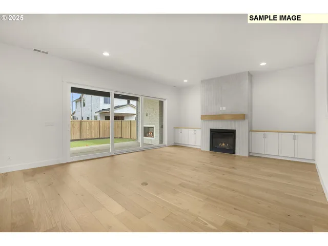 a view of empty room with wooden floor and fireplace