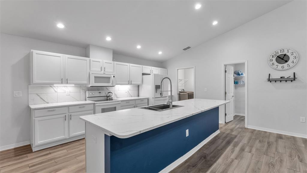 501 Interlock Street Lake Alfred, FL 33850 - Photo 12 of 49 a kitchen with a sink a stove a refrigerator and white cabinets with wooden floor