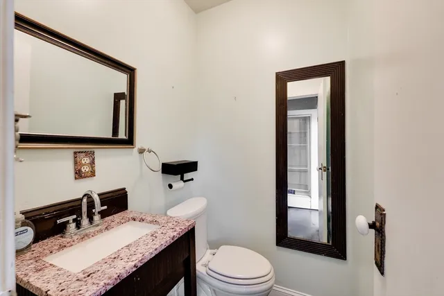 a bathroom with a granite countertop sink a toilet and mirror