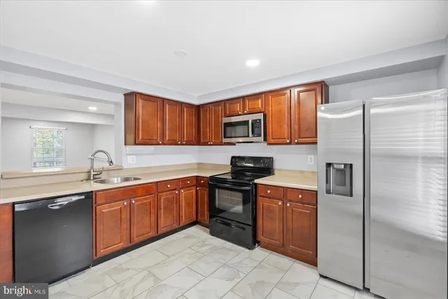 a kitchen with stainless steel appliances granite countertop a sink stove refrigerator and cabinets