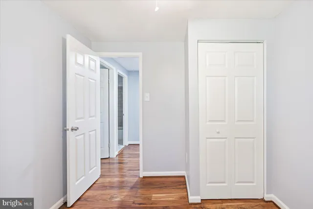 an empty room with wooden floor and closet area