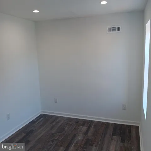 a view of an empty room with wooden floor and closet