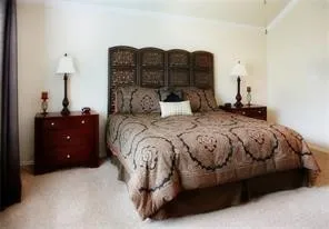 a spacious bedroom with a bed dresser and a lamp