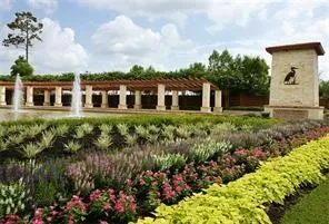 a front view of a house with a yard and fountain in middle of the road