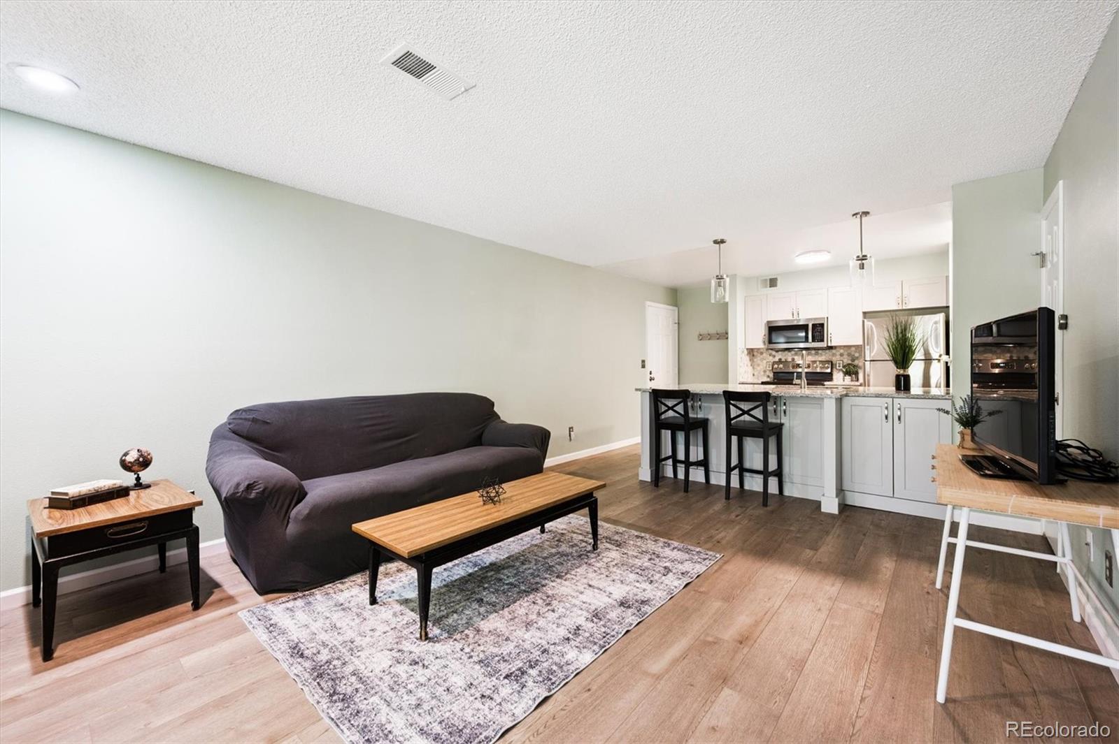 2575 South Syracuse Way, Unit L103 Denver, CO 80231 - Photo 11 of 21 a living room with furniture and a wooden floor