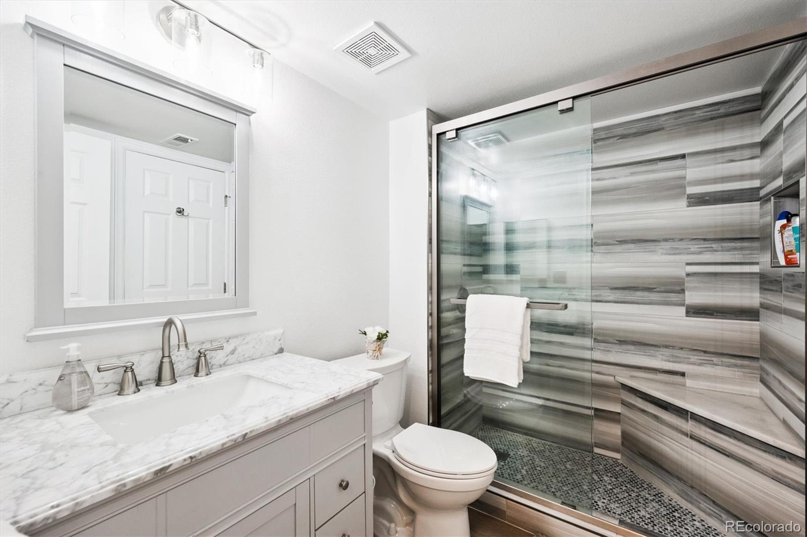 2575 South Syracuse Way, Unit L103 Denver, CO 80231 - Photo 12 of 21 a bathroom with a granite countertop sink toilet and shower