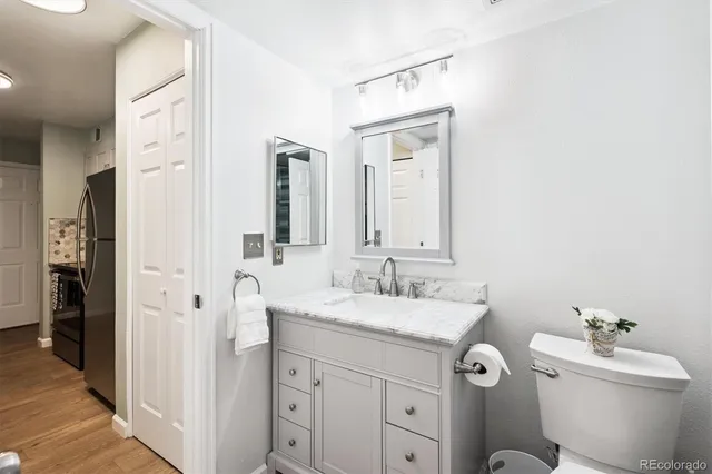 a bathroom with a granite countertop sink mirror vanity and toilet
