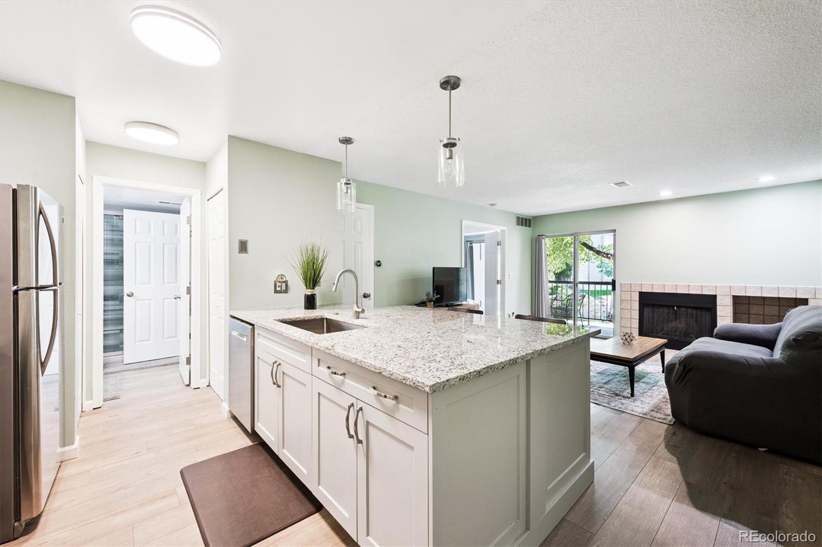 2575 South Syracuse Way, Unit L103 Denver, CO 80231 - Photo 3 of 21 a large white kitchen with a center island and stainless steel appliances