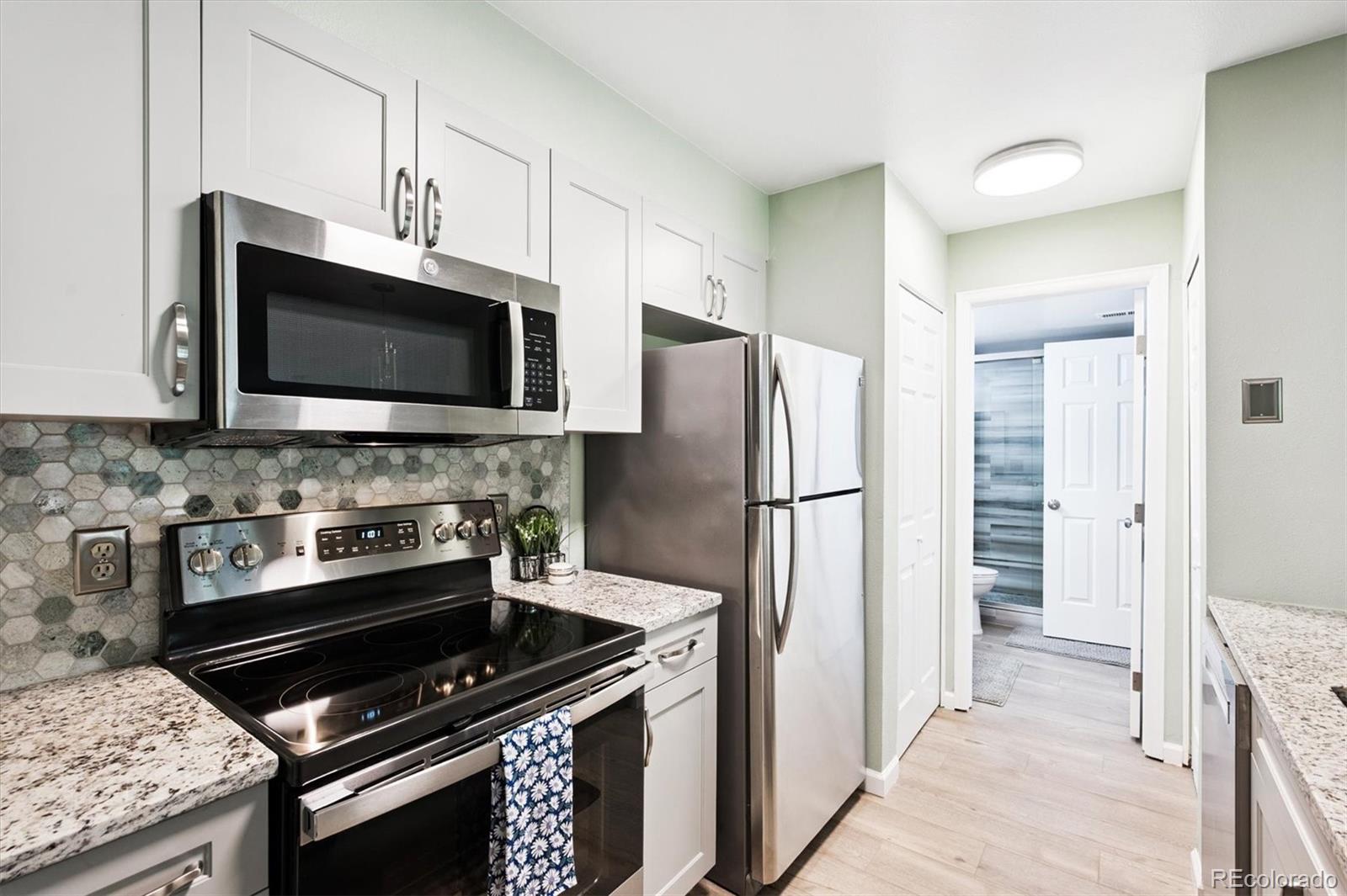 2575 South Syracuse Way, Unit L103 Denver, CO 80231 - Photo 4 of 21 a kitchen with a stove and a microwave