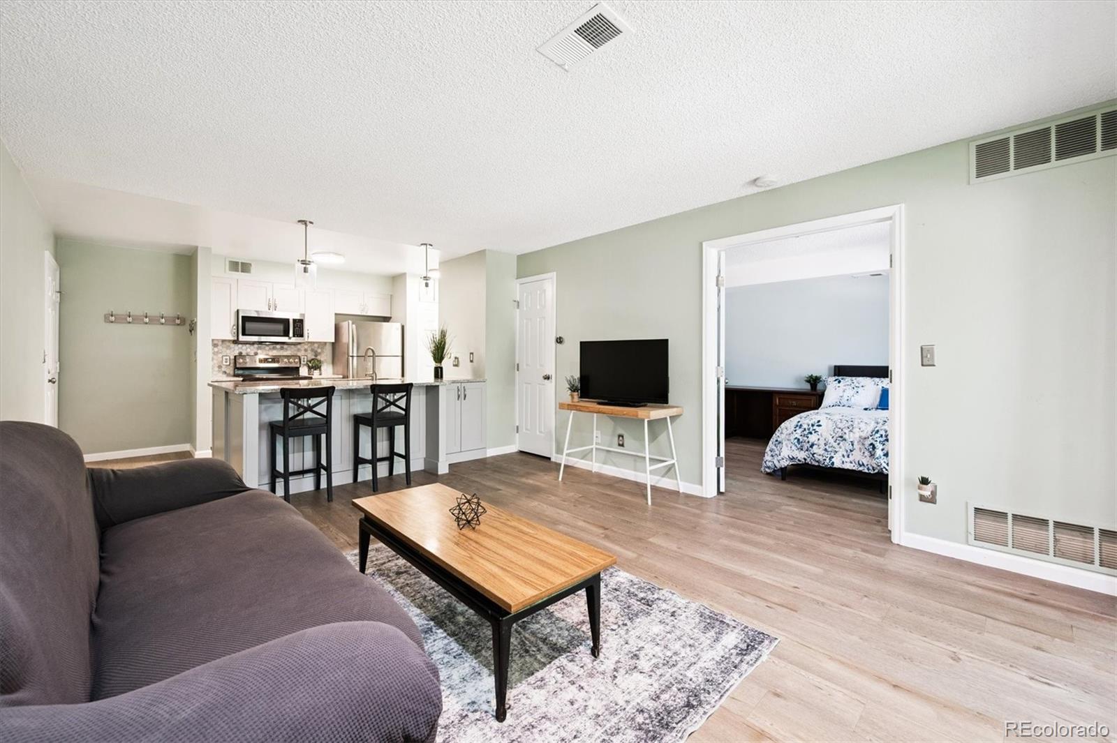 2575 South Syracuse Way, Unit L103 Denver, CO 80231 - Photo 10 of 21 a living room with furniture and a flat screen tv