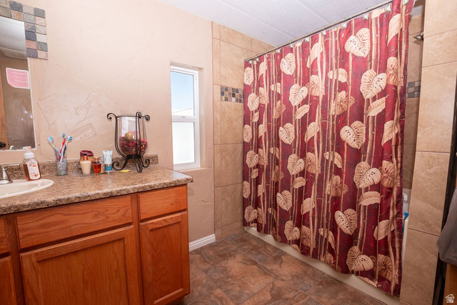 855 East 300 N Street Beaver, UT 84713 - Photo 23 of 44 Bathroom featuring wood cabinetry, a speckled countertop with an integrated sink, tile flooring, and a tiled shower surround with decorative accent tiles