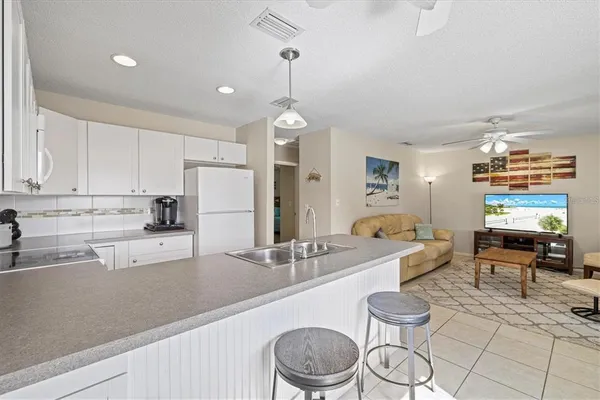 a kitchen with stainless steel appliances a sink a stove a refrigerator cabinets and living room view