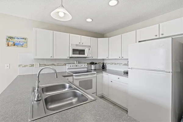 a white kitchen with sink and white stainless steel appliances