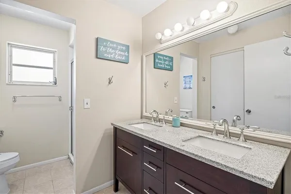 a bathroom with a granite countertop sink a toilet and a mirror