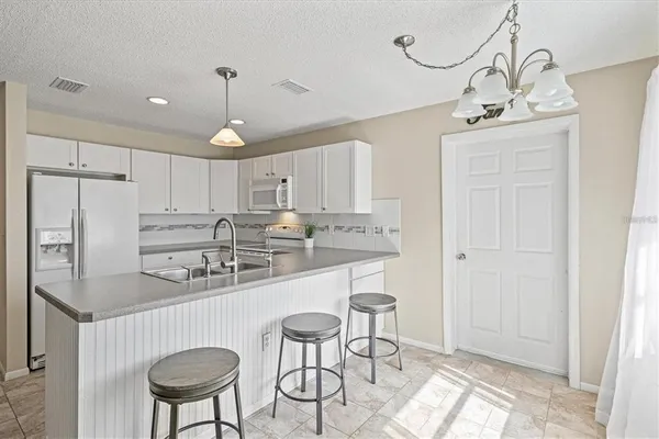 a kitchen with stainless steel appliances granite countertop a sink a stove a refrigerator cabinets and chairs