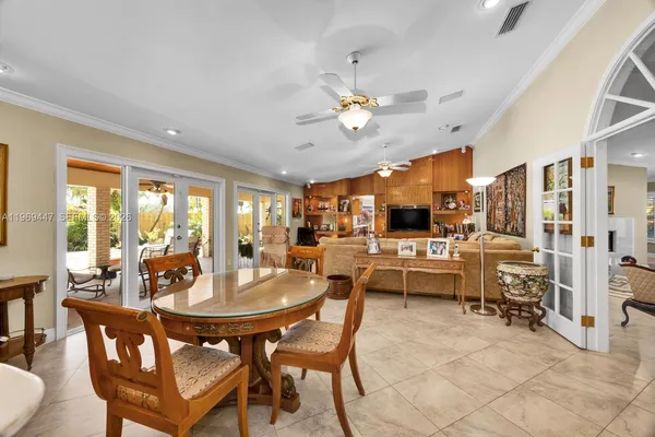 a dining room with wooden floor a chandelier fan a wooden table and chairs