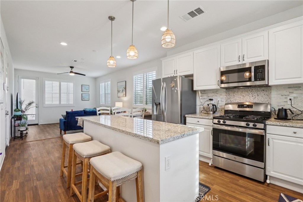 7656 Channel View Street Chino, CA 91708 - Photo 4 of 40 a large kitchen with stainless steel appliances granite countertop a stove a sink dishwasher a refrigerator white cabinets and wooden floor