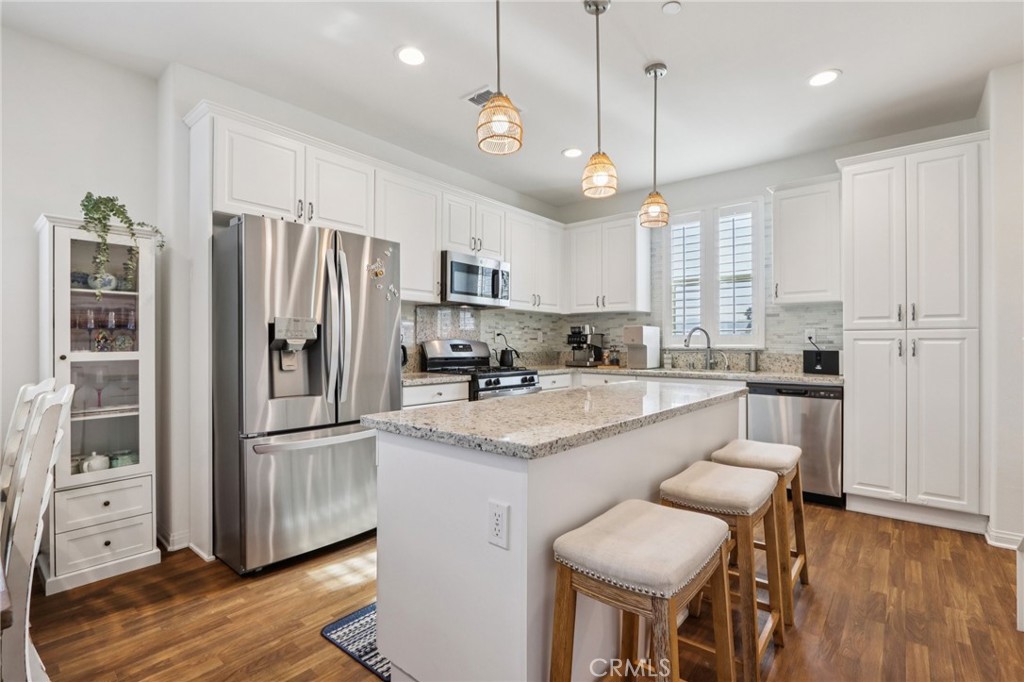 7656 Channel View Street Chino, CA 91708 - Photo 9 of 40 a kitchen with stainless steel appliances granite countertop a refrigerator a sink dishwasher a stove and white cabinets with wooden floor