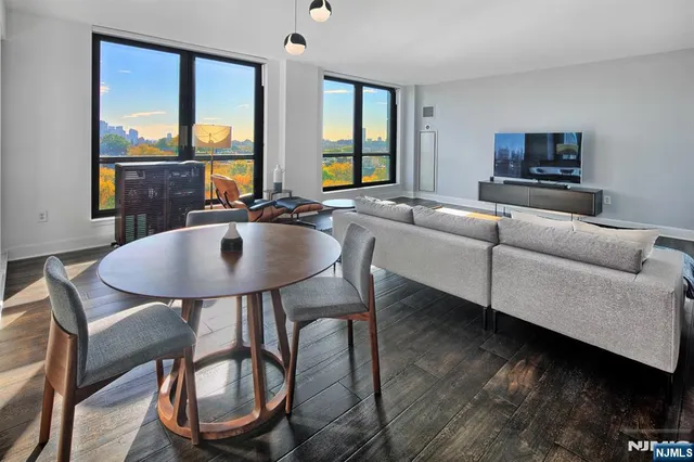 a living room with furniture a flat screen tv and floor to ceiling window