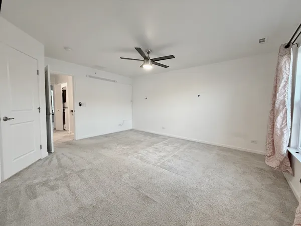 an empty room with a ceiling fan and a window