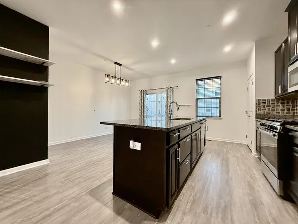 a kitchen with granite countertop a refrigerator a sink and wooden floor