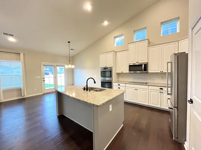 a kitchen with stainless steel appliances granite countertop a sink a stove and a refrigerator