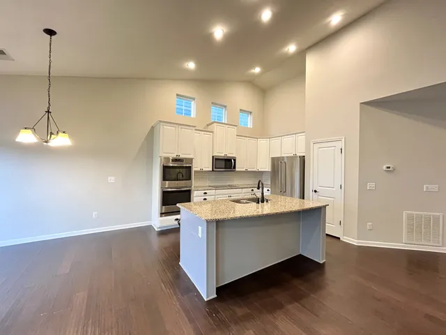 a kitchen with stainless steel appliances a sink stove and wooden floor
