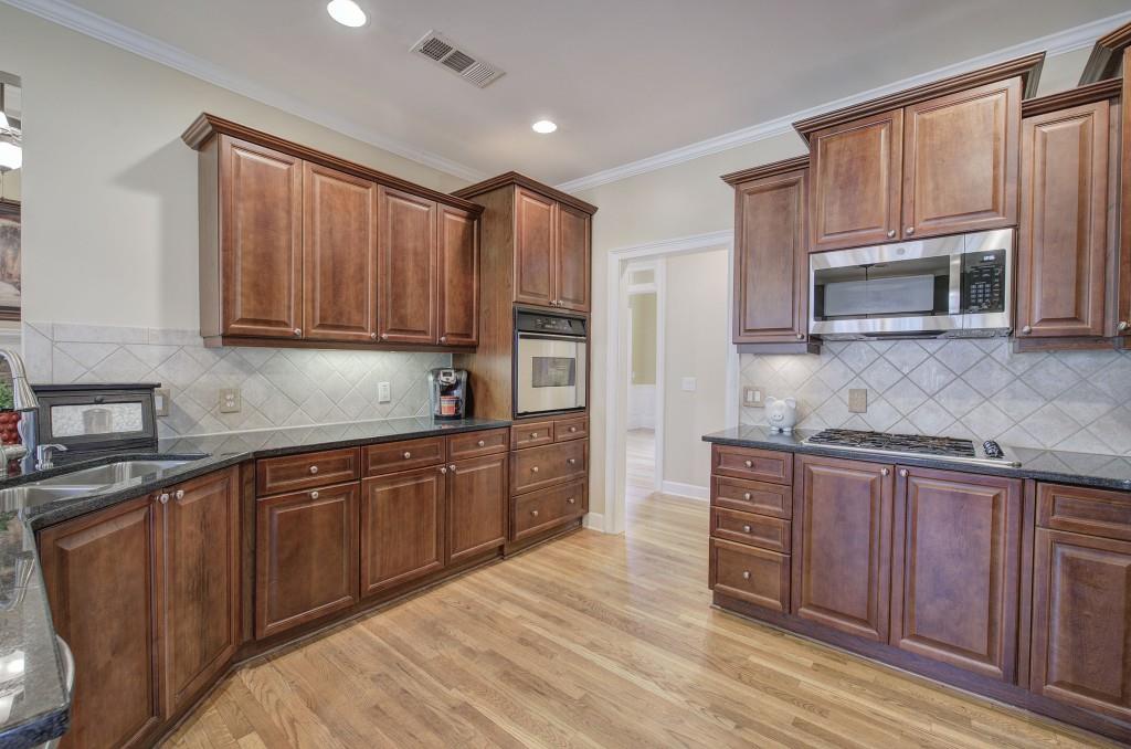 302 Waterfall Court Canton, GA 30115 - Photo 29 of 80 a kitchen with stainless steel appliances granite countertop wooden cabinets a stove a sink and dishwasher with wooden floor