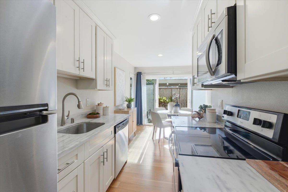 280 Easy Street, Unit 307 Mountain View, CA 94043 - Photo 16 of 30 a kitchen with stainless steel appliances a stove a sink dishwasher and white cabinets with wooden floor