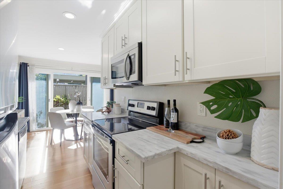 280 Easy Street, Unit 307 Mountain View, CA 94043 - Photo 17 of 30 a kitchen with a white stove top oven and white cabinets with wooden floor