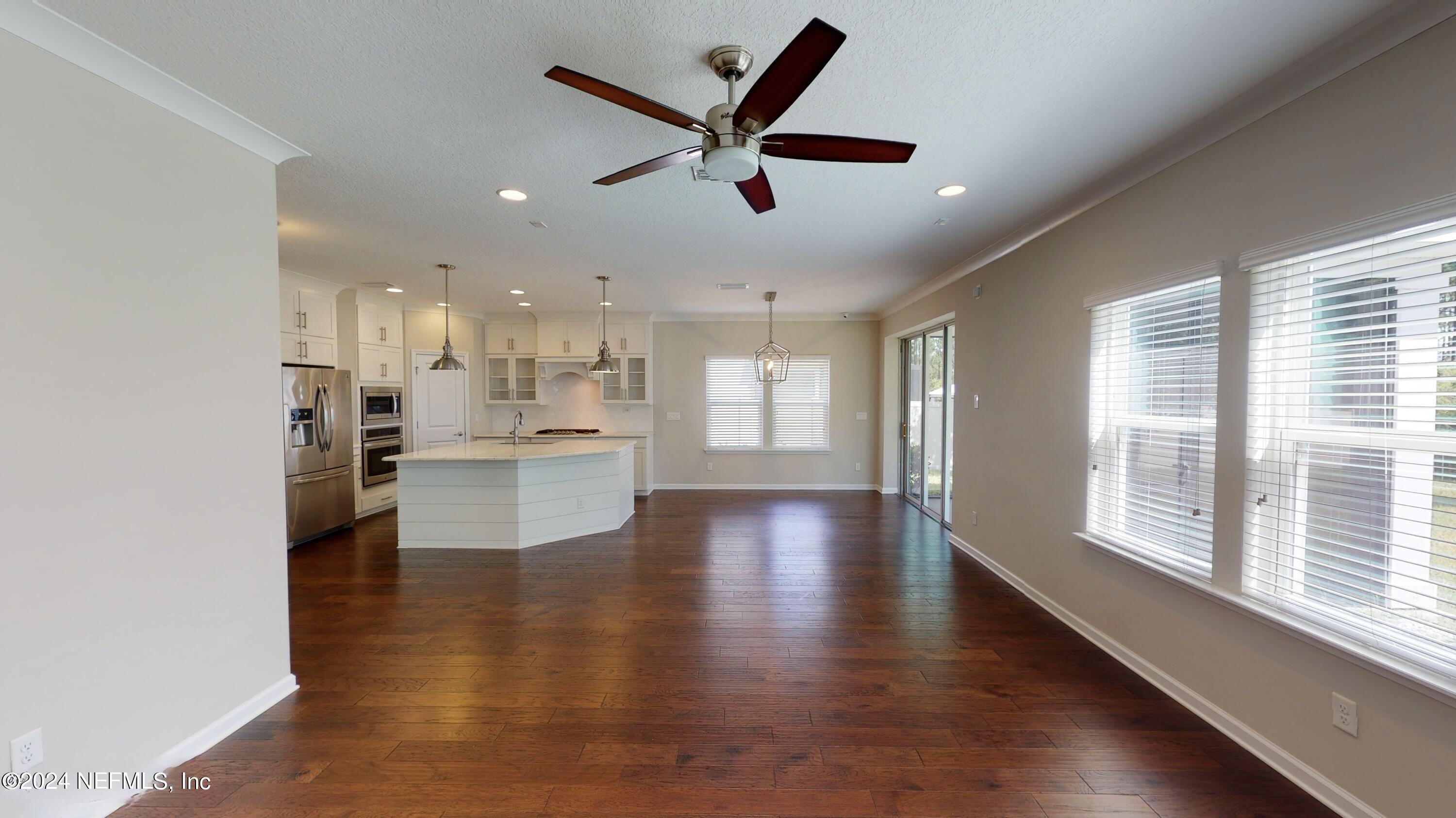 212 Concave Lane St. Augustine, FL 32095 - Photo 9 of 24 a view of an empty room and kitchen with wooden floor and a window