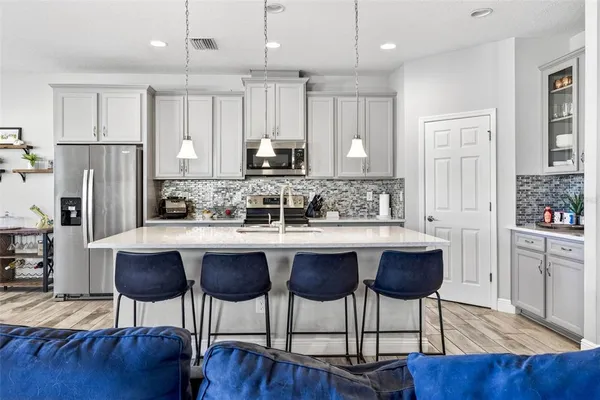 a living room with furniture kitchen view and a large window