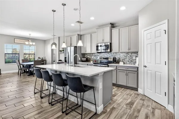 a kitchen with stainless steel appliances granite countertop a dining table chairs refrigerator and cabinets