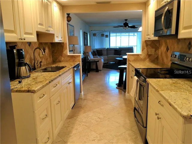 a kitchen with stainless steel appliances granite countertop a stove a sink a refrigerator and a cabinets