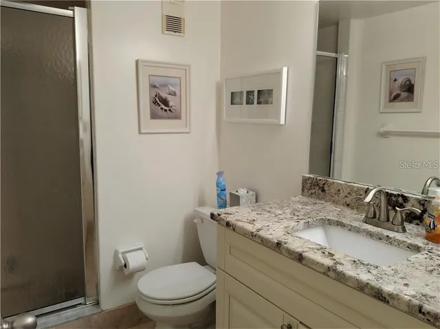a bathroom with a granite countertop sink mirror vanity and toilet