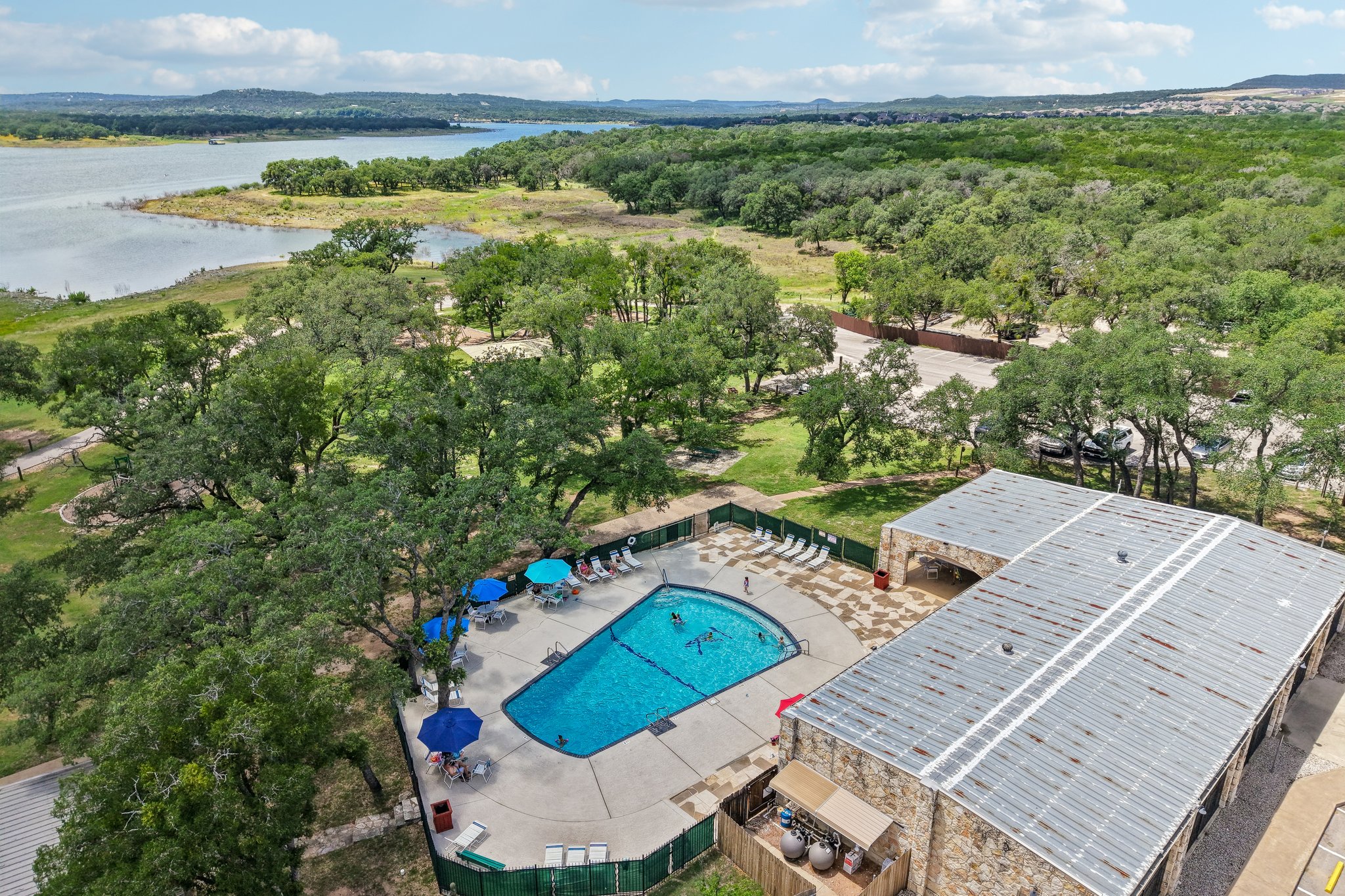 20609 Bridle Path Road Lago Vista, TX 78645 - Photo 25 of 30 An aerial perspective reveals a sparkling community pool nestled amongst lush trees, beside a scenic waterfront.