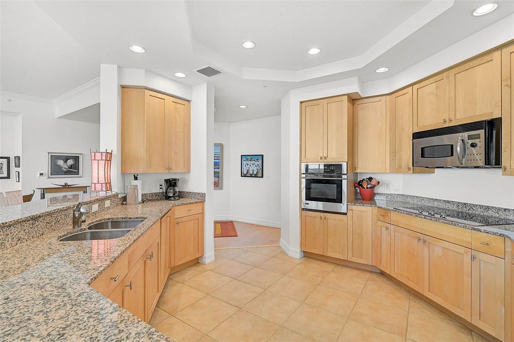 3603 North Point Road, Unit 702 Osprey, FL 34229 - Photo 11 of 61 a large kitchen with stainless steel appliances granite countertop a large stove top oven a sink dishwasher a dining table and chairs with wooden floor