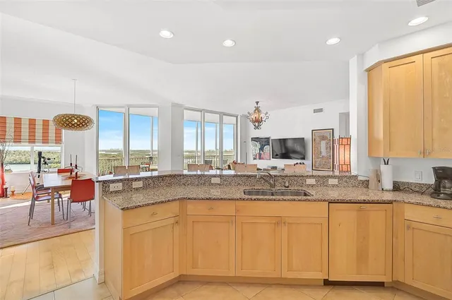 a large white kitchen with kitchen island granite countertop a sink and white cabinets