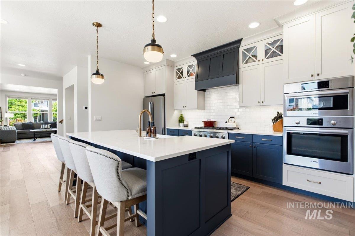 3794 South Single Tree Avenue Boise, ID 83716 - Photo 20 of 50 Kitchen featuring a large island with white countertop, two-tone cabinetry, stainless steel appliances, and wood-finish flooring