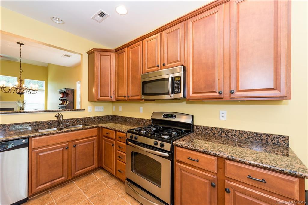 717 Prospect Lane, Unit 46 Fort Mill, SC 29708 - Photo 5 of 19 a kitchen with stainless steel appliances granite countertop a sink a stove a microwave cabinets and a counter top space