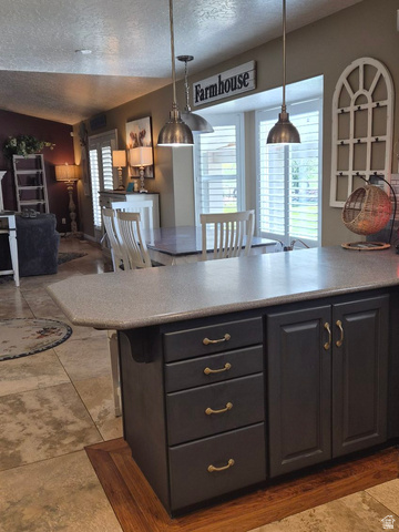 1697 West 2450 Vernal, UT 84078 - Photo 36 of 36 Kitchen featuring dark cabinets, a textured ceiling, open floor plan, hanging light fixtures, and a breakfast bar area