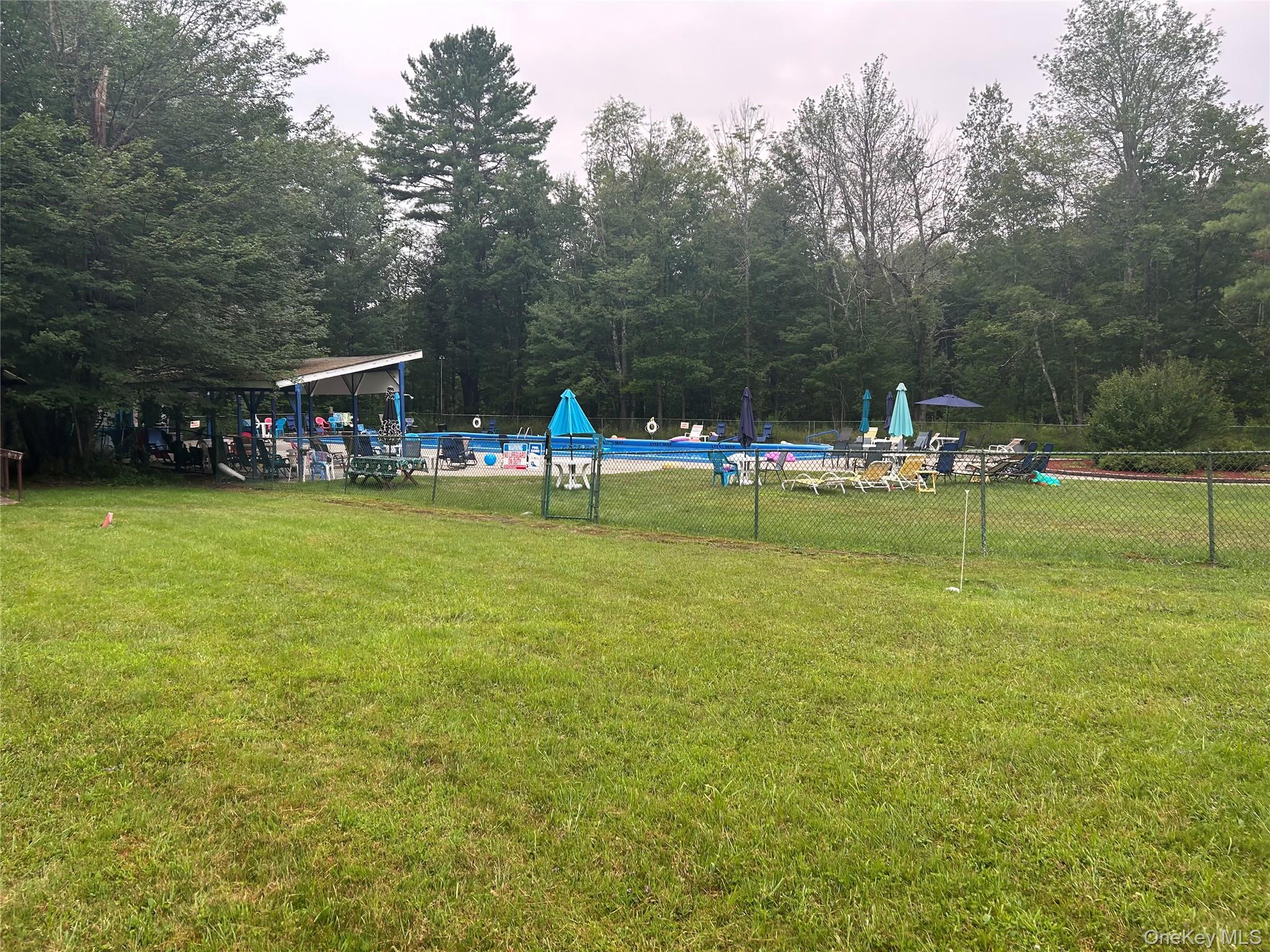 52 Greentree Road, Unit 12A Monticello, NY 12701 - Photo 8 of 11 a view of a swimming pool with a bench and trees