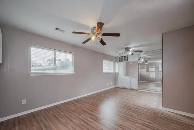 a view of empty room with wooden floor and fan