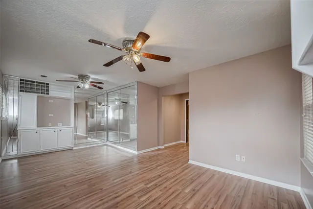a view of a room with wooden floor and a ceiling fan
