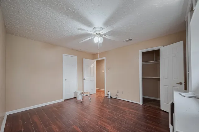 an empty room with wooden floor and a ceiling fan