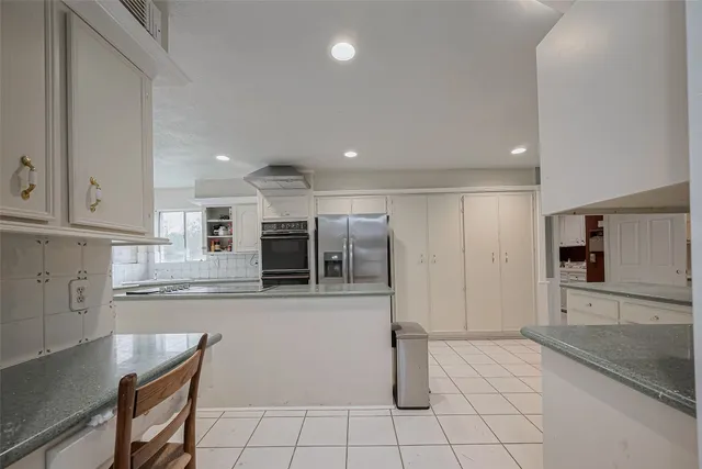 a kitchen with stainless steel appliances granite countertop a refrigerator and a stove top oven