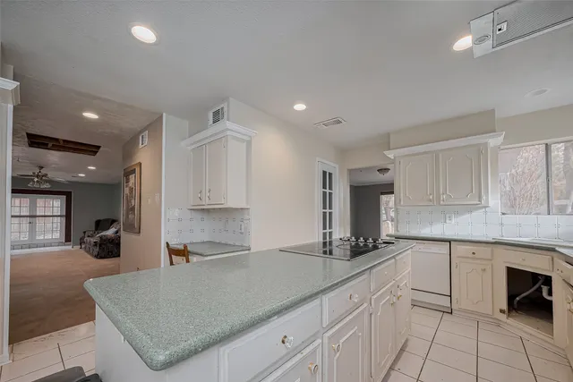 a kitchen with a sink dishwasher a stove and white cabinets with wooden floor